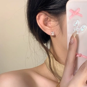 Elegant 999 silver bow pearl stud earrings with zircon on woman's earlobe