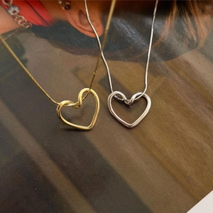 Detailansicht der gedrehten Herzanhänger in Gold und Silber mit eleganten Schlangenketten