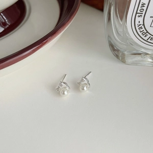 Detailed view of silver bow pearl earrings with zirconia on a minimalist background