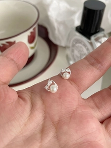 Close-up of 999 sterling silver bow earrings with sparkling zircon and white pearls