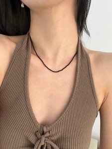 Close-up of minimalist black spinel beaded choker necklace worn by a female model