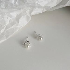 Close-up of 999 silver bow earrings with sparkling zirconia and round white pearls