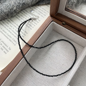 Detail of black faceted spinel beaded necklace on a linen lining inside a wooden jewelry box