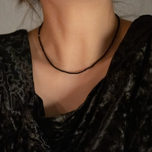 Close-up of minimalist thin black spinel beaded necklace worn by a model on neck