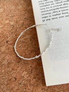 Detail of S925 sterling silver beaded bracelet with heart charm on cork background