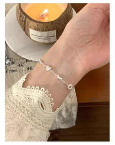 Bracelet en argent sterling S925 avec breloques cœur et nœud sur le poignet d'une femme