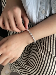 Wrist view of a minimalist S925 sterling silver beaded bracelet with polished cat eye beads