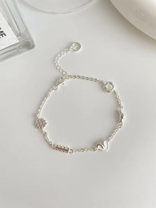 Détail du bracelet en argent S925 avec breloques gaufre et cœur sur surface blanche