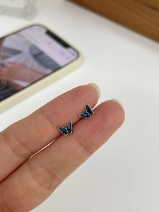 Close-up of mini butterfly stud earrings with blue gradient enamel and silver metal edges