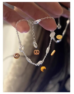 Détail d'un bracelet en argent avec breloques en forme de croissant et de gaufre