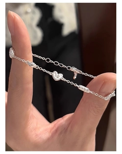 Vue détaillée du bracelet en argent sterling S925 avec pendentifs cœur sur une main
