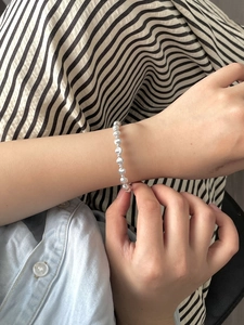 Close-up of minimalist S925 sterling silver beaded bracelet worn on wrist with sleek metallic luster