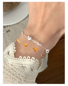 Détail d'un bracelet en argent sterling S925 avec breloques cœur et fleurs sur dentelle