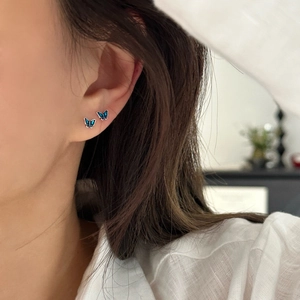 Elegant 999 sterling silver mini blue butterfly stud earrings worn by a model