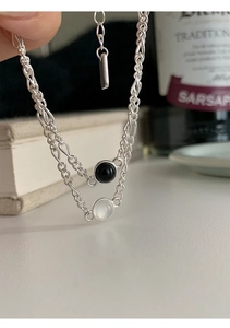 Gros plan d'un bracelet double chaîne en argent S925 avec pendentifs en agate noire et opale