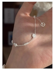 Gros plan d'un bracelet en argent S925 avec breloques cœur et gaufre sur la main