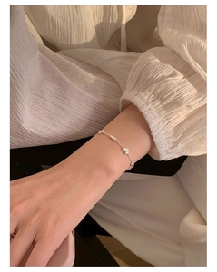 Gros plan d'un bracelet en argent sterling S925 avec breloques cœur sur un poignet