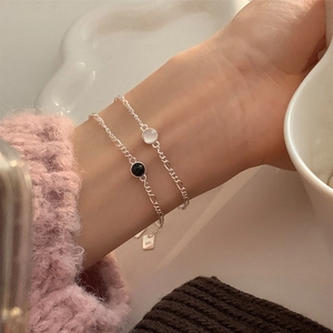 Détail de bracelets en argent fin S925 avec agate noire et blanche sur le poignet d'un modèle