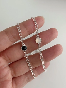 Détail de chaînes Figaro en argent 925 avec breloques rondes en onyx noir et opale blanche
