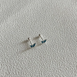Detail of blue enamel butterfly stud earring with screw back ball on textured surface