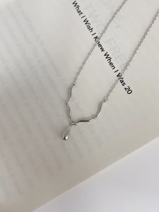 Detail of S925 sterling silver necklace with teardrop pendant on an aesthetic book page