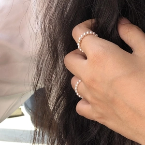 Dettaglio degli anelli elastici in argento S925 con perle bianche su un modello