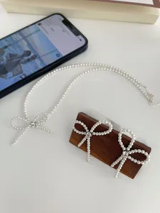 Detail of S925 silver bow necklace and earrings set featuring white pearls and zircon stones