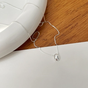 Detailed view of a silver oval bean pendant on a delicate box chain for women