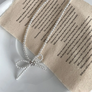 Elegant S925 silver pearl necklace with zircon bow pendant on white ceramic plate