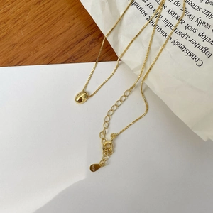 Detail view of gold bean pendant on box chain with S925 sterling silver stamp