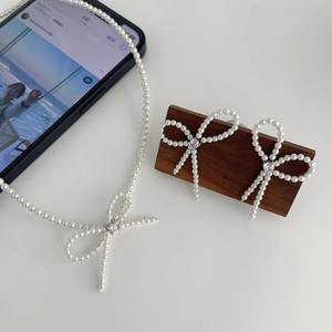 Elegant pearl bow necklace and earring set with sparkling zircon on dark wooden base