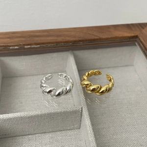 Detail der goldenen und silbernen Croissant-Twist-Ringe in einer Holz-Schmuckschatulle