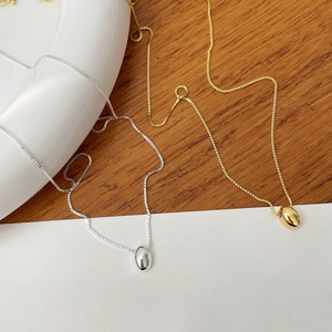Close-up of gold and silver minimalist oval bean pendants on fine box chains