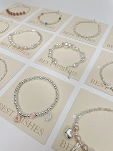 Flat lay of diverse S925 silver pearl bracelets with colorful heart and flower charms
