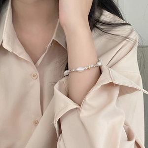 Close-up of baroque pearl bracelet with gold and silver beads worn on female wrist