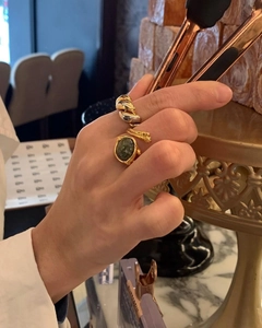 Nahaufnahme von Gold-Croissant-Ring und Vintage-Ring mit grünem Edelstein an der Hand