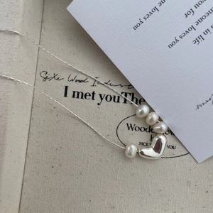 Detail of silver heart pendant with freshwater pearls on a fine chain necklace