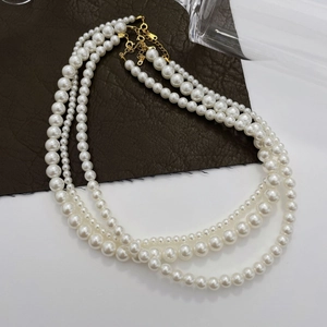 Detail of a triple-layered pearl necklace with golden clasp and adjustable chain