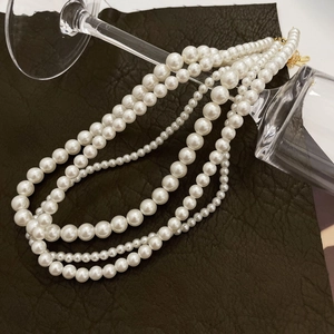Macro shot of tiered white pearl necklaces with golden clasps over glass and leather