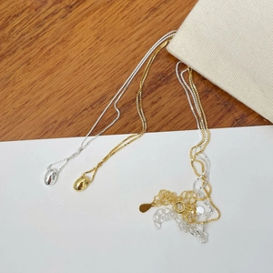 Detail view of gold and silver bean pendants on fine box chains with extension tails