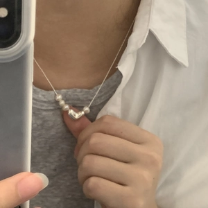 Detail view of a S925 silver heart pendant necklace with freshwater pearls worn by a model