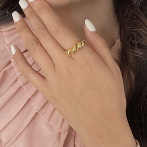 Detailansicht eines vergoldeten Croissant-Rings mit gedrehter Textur getragen am Finger