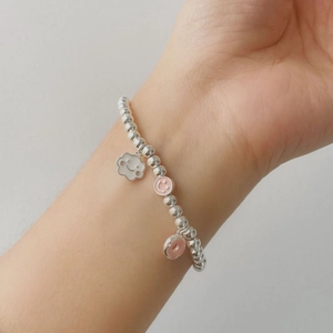 Detailed shot of silver beaded bracelet with cloud, smiley and donut charms