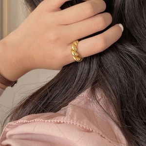 Nahaufnahme eines vergoldeten Croissant-Rings mit gedrehter Textur an einem Finger