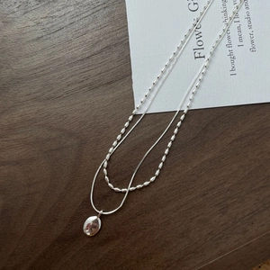 Detail of S925 silver double layer necklace with oval pendant on dark wooden background