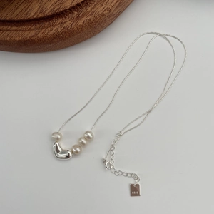 Detail of S925 silver necklace with four freshwater pearls and a heart pendant