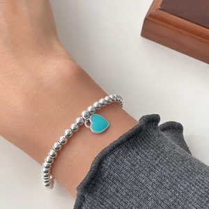 Close-up of S925 silver beaded bracelet featuring a turquoise heart charm on wrist
