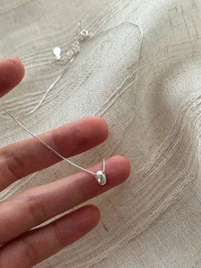Close-up of minimalist 925 sterling silver bean pendant with fine box chain and extender