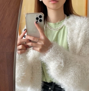 Detail shot of a layered pearl necklace paired with a white fuzzy cardigan sweater