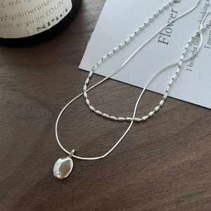 Minimalist S925 silver layered necklace with oval pendant on a dark wood background